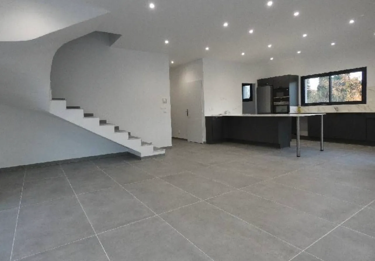Pièce de vie ouverte avec carrelage grand format gris clair posé en quinconce sur grande surface